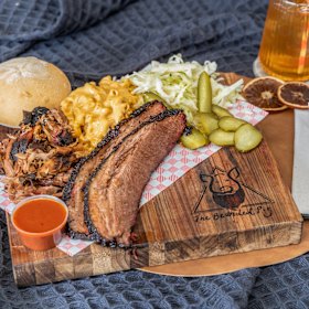 Barbecue pack for two featuring brisket and smoked pulled pork, green apple slaw, pickles, house barbecue sauce, mac and cheese and a milk bun.