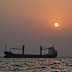 The sun sets over commercial vessels anchored in the Strait of Hormuz off Bandar Abbas, Iran.
