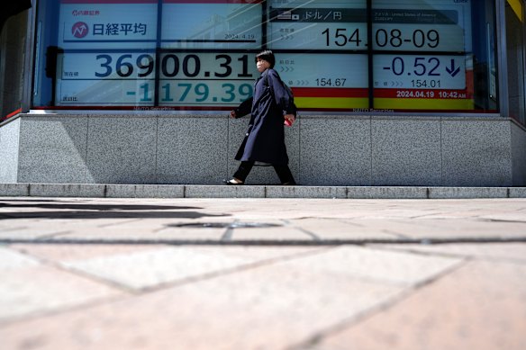 A person walks in front of an electronic stock board showing Japan’s Nikkei 225 index at a securities firm in Tokyo.