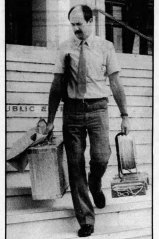 Constable Phil Case carries out the hoax bomb in a paper bag from Parliament House in Canberra.