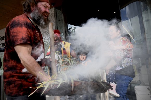 Locky Magic Dennis (left), Ruby Dykes (centre) and Fleur Magic Dennis during a smoking ceremony outside the Coroners Court on Friday.