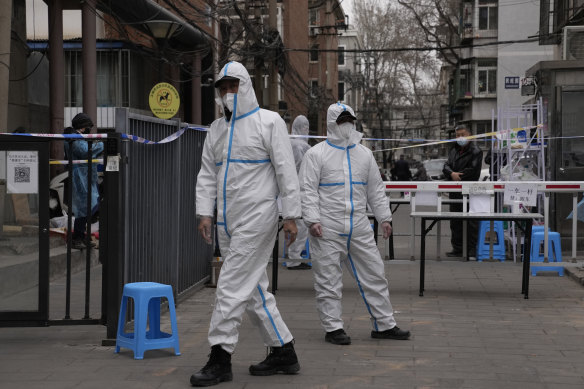 Workers in PPE overalls guard an entrance to a community under lockdown in Beijing in March.