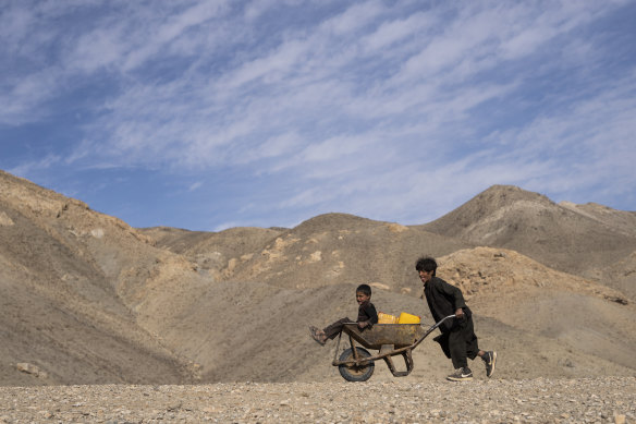 A boy pushes a wheelbarrow with canisters and his younger brother, on their way to collect water from a stagnant pool about 3 kilometres from their home in Kamar Kalagh village outside Herat, Afghanistan.