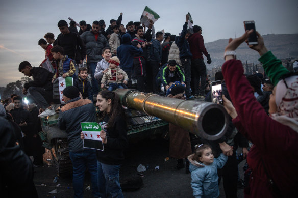 People sing and dance on top of a destroyed tank in Umayyad Square in Damascus, Syria, following the fall of the Assad regime.