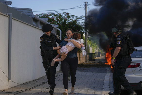 Israeli police officers evacuate a woman and a child from a site hit by a rocket fired from the Gaza Strip on Saturday.