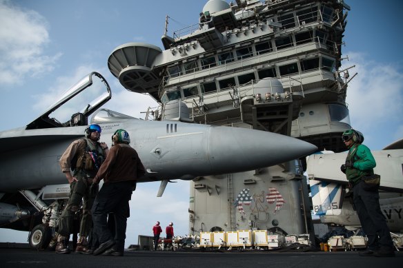 A pilot speaks to a crew member on the deck of the USS Abraham Lincoln aircraft carrier in the Arabian Sea. 