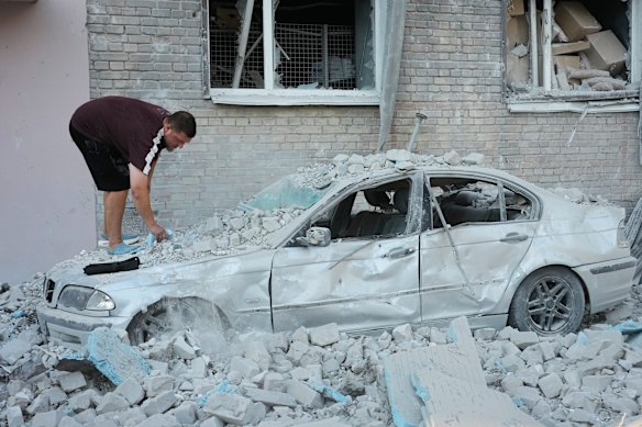 Un residente di Kiev ispeziona un'auto danneggiata.