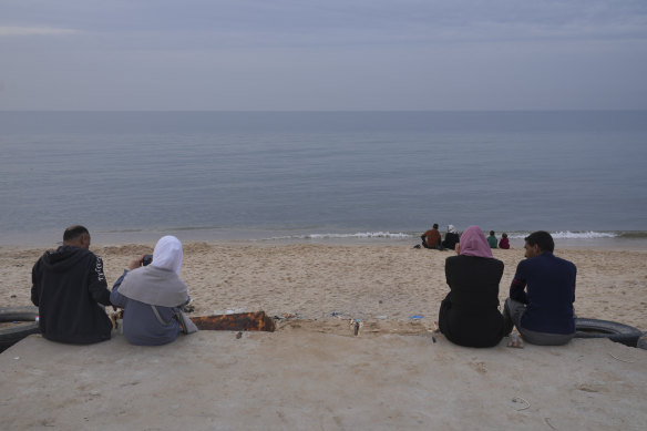 Displaced Palestinians take a break on the beach in Deir al Balah, Gaza Strip, during the temporary ceasefire between Israel and Hamas in November. Few details of the offshore pier are available.
