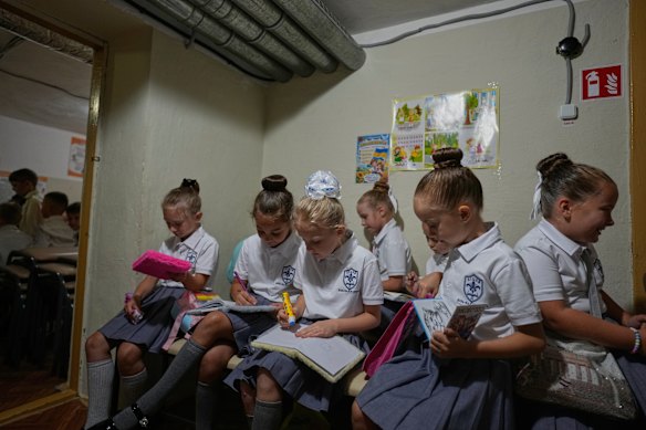 Schoolgirls continue working in a bomb shelter during a Russian air attack on the first day of the new school year.
