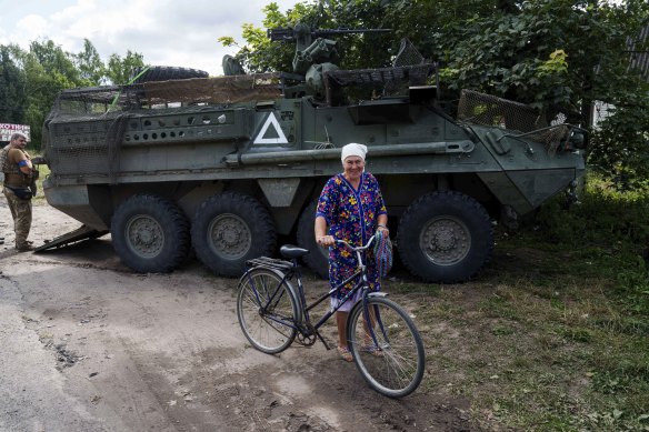 A local woman hauls her bicycle in front of Ukrainian APC near the Russian-Ukrainian border.