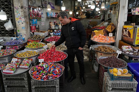A shopkeeper arranges items at his shop around the traditional grand bazaar of Tehran on Sunday. Despite the war, fresh produce remains widely available in Iran.