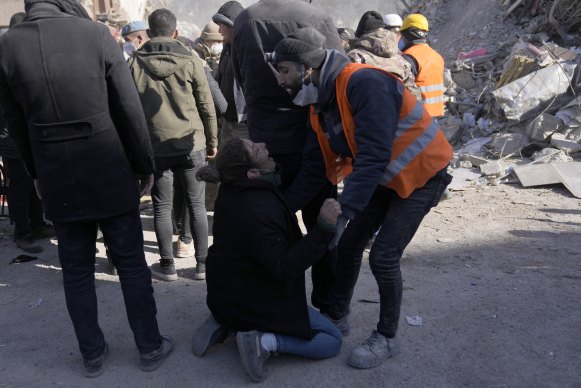 一名妇女在土耳其东南部 Kahramanmaras 的一座被毁建筑物前倒下” loading=