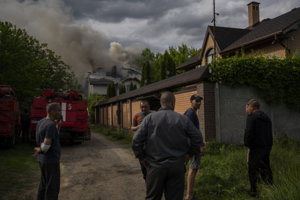 Neighbours gather around a house on fire that was hit during a Russian attack with a cluster-type munition in Kharkiv, eastern Ukraine.