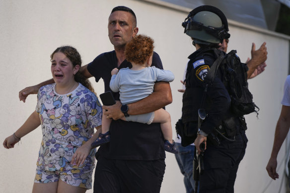 Israeli police officers evacuate a family from a site hit by a rocket fired from the Gaza Strip, in Ashkelon, southern Israel. 