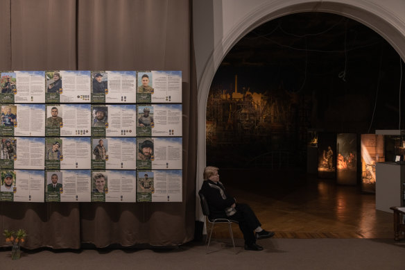 A museum worker sits next to the portraits of members of the ‘Azov’ unit killed in Mariupol during a Russian attack last year. The photos are part of a new exhibition about the defence of the Azovstal steelworks.