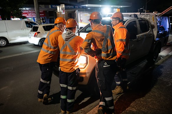 Workers gather to look at plans for the night ahead.