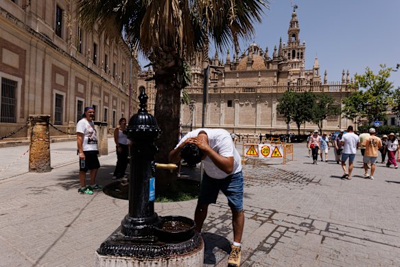Un uomo si rinfresca presso una fontana pubblica a Siviglia, in Spagna.