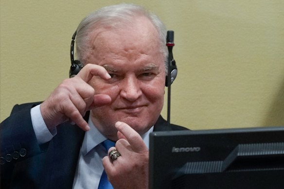 Mladić mimics photographers taking pictures in the courtroom in The Hague in 2021.