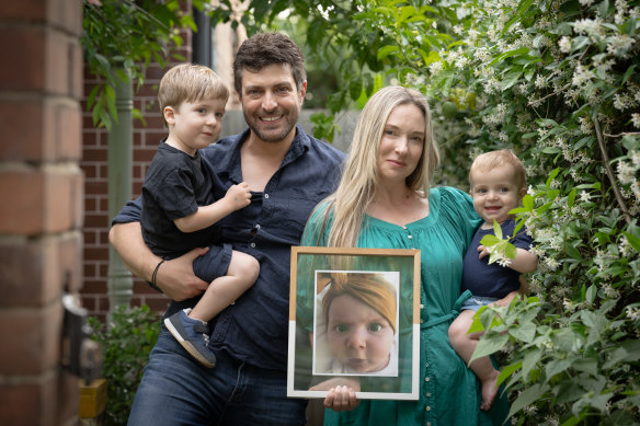Rachael and Jonathan Casella with their boys Izaac (two) and Joshua (10 months), and a photo of their daughter Mackenzie who was born with spinal muscular atrophy and died just seven months later.