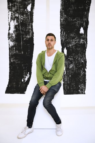 Visual artist Jonathan Jones with two prints of river red gum timber slabs, part of his collaboration with Uncle Stan Grant snr.