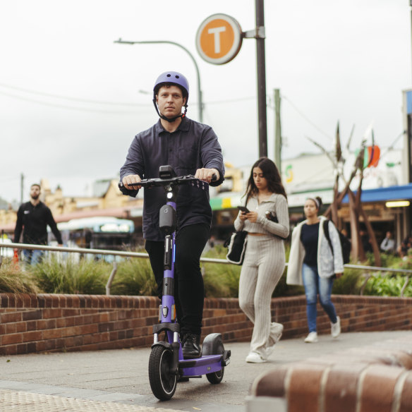 Inner West Greens councillor Dylan Griffiths on a Beam e-scooter outside Kogarah train station.