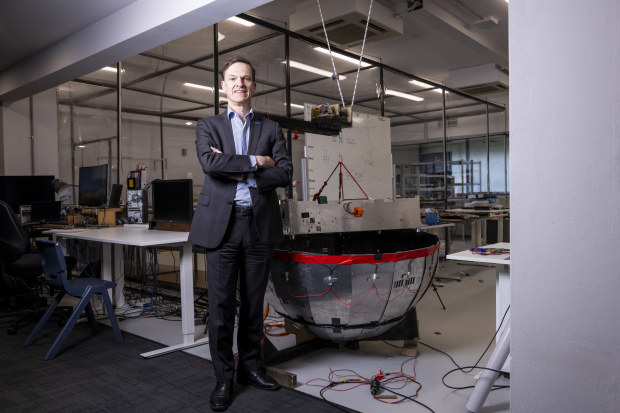 Skykraft CEO Dr Michael Frater stands in a workshop with one of SkyKraft’s satellites.