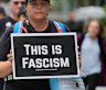 Ella Fowler carries a sign as she and other anti-Trump, anti-fascism protesters march as part of the “Good Trouble Lives On” national day of action, in Chicago.