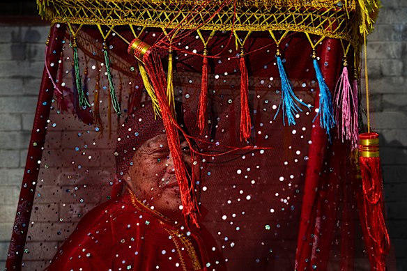 A man dressed in festive clothing waits to take part in a procession to celebrate Xiao Nian, or Little New Year, in the historic part of Beijing, China.