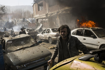 An injured man uses a piece of timber as a crutch to move away from the scene of a bomb blast in central Kabul, 2019.