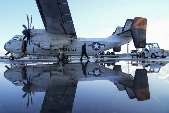 A crew member walks next to a C-2 Greyhound on the tarmac of Manama airport, Bahrain, before a flight to the USS aircraft carrier Dwight D. Eisenhower.