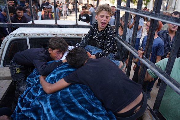 Palestinian children mourn over the body of their father, Mohammed Ghaben, who was killed while heading to an aid distribution hub, in Gaza City.