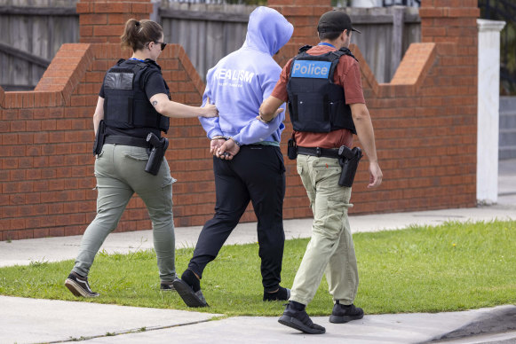 A man is led away by officers during raids targeting the Dandenong Thunder soccer club.