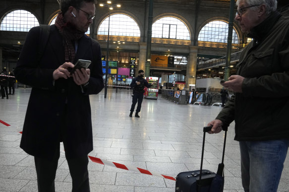 Travellers wait behind the police tape at the Gare du Nord train station in Paris. 