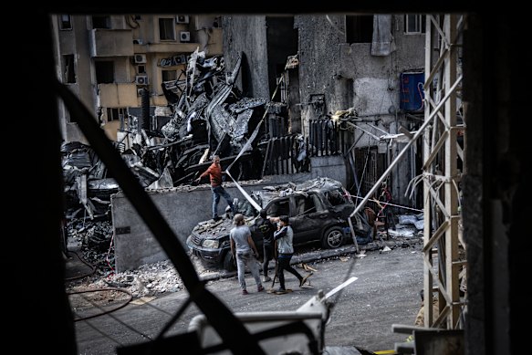 People attempt to remove a vehicle destroyed in an Israeli airstrike on April 9 in Beirut, Lebanon.