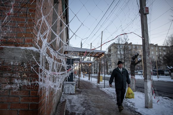 A man walks on a sidewalk covered in anti-drone netting in Izyum, Ukraine. 