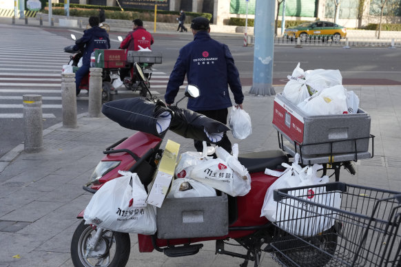 Delivery drivers prepare with their orders in Beijing on Friday. Delivery apps are overwhelmed as residents choose not to go out to avoid being thrown into quarantine facilities for being a COVID close contact.