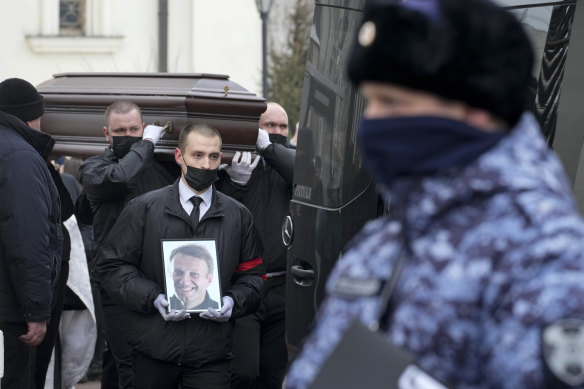Workers carry the coffin and a portrait of Alexei Navalny out of the Church of the Icon of the Mother of God Soothe My Sorrows.