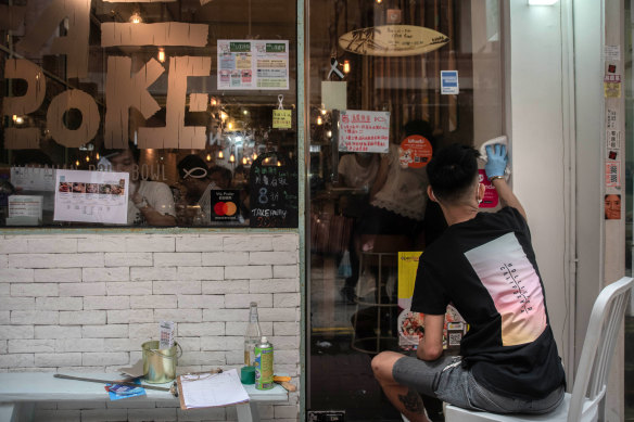 A man removes notes supporting the pro-democracy movement from the door of restaurant in Hong Kong. Residents and businesses have begun to self-censorship after the enactment of new national security laws.