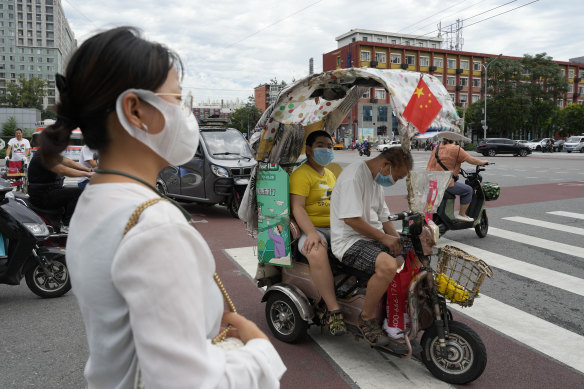 A man and a child wearing masks sit in an electric tricycle with a Chinese national flag in Beijing. A Chinese think tank issued a rare public disagreement on Monday with the ruling Communist Party’s severe “zero COVID” policy.