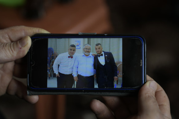 Mohammed Shula displays a picture on his phone of himself, centre, with his sons Bilal and Yazan.
