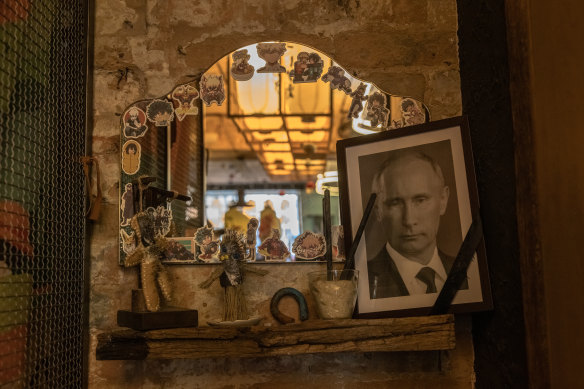 A portrait of Vladimir Putin, with a black ribbon over it commonly used for the deceased, is placed next to voodoo dolls, at a restaurant on March 18 in Kyiv, Ukraine. 