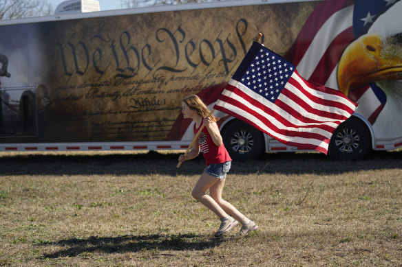 Lola Lee runs with a US flag during a “Take Our Border Back” convoy and rally in Quemado, Texas, on Saturday. The convoy supported the Texas governor in his fight with the Biden administration over control of the border.