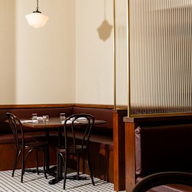 Floors have black and white tiles and fluted glass separates booths. 