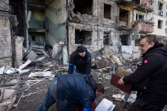 People salvage belongings from a residential apartment block that was hit by Russian shelling in Kyiv.