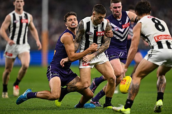 Jamie Elliott van de Magpies wordt aangepakt door Heath Chapman of the Dockers.