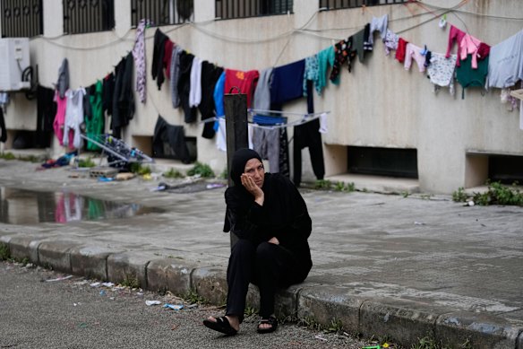 A displaced woman who fled Israeli airstrikes in southern Lebanon sits outside a school turned into a shelter in the Lebanese port city of Sidon.