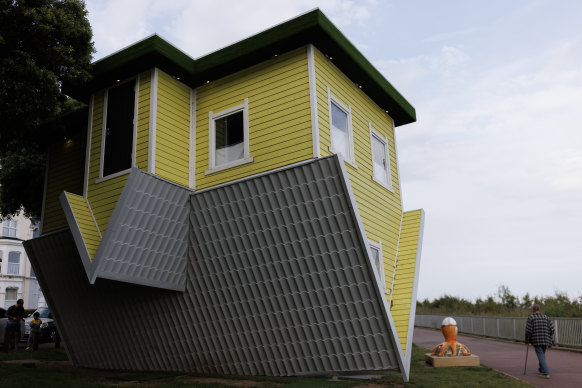 A man walks past the “Upside Down House” in Clacton-on-Sea.