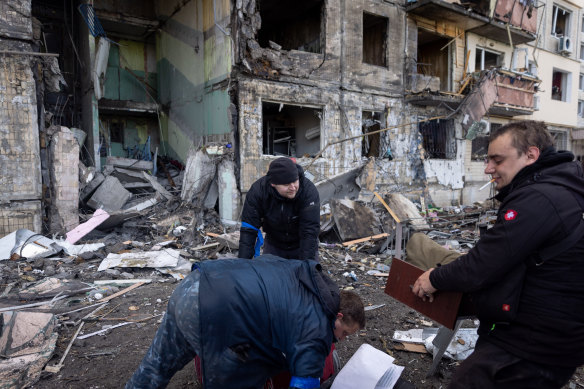 People salvage belongings from a residential apartment block that was hit by Russian shelling in Kyiv.