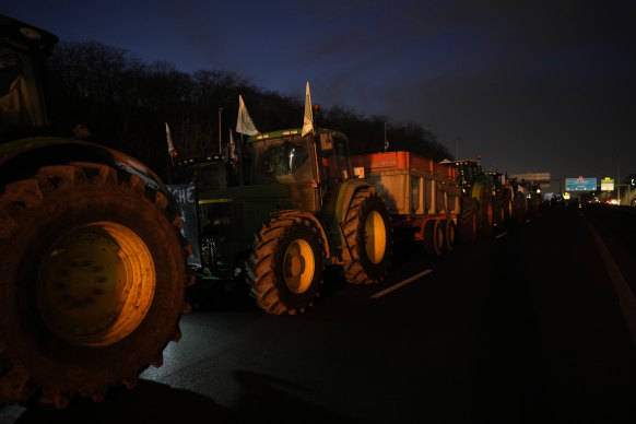 Tractors line up as farmers block a highway.
