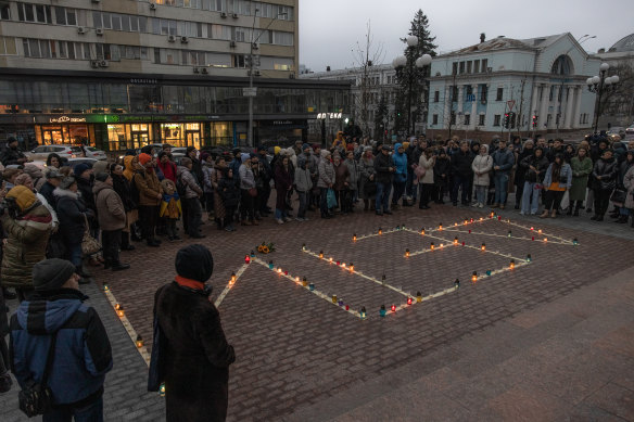 People gather next to candles that are put in order to depict the word “Children” during a memorial event on the anniversary of the Mariupol Theatre Airstrike, in front of The National Opera of Ukraine, on March 16, in Kyiv.